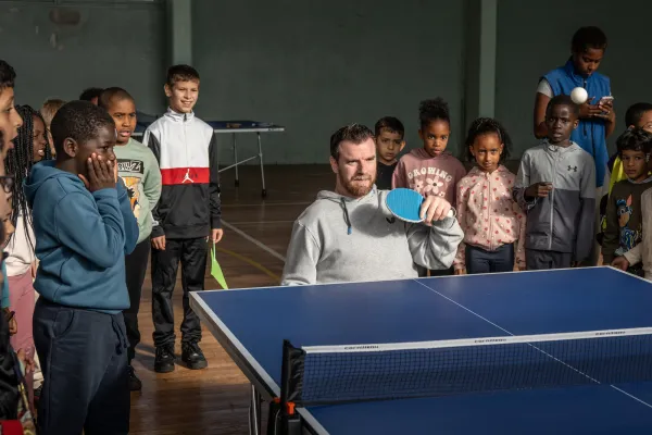 Florian Merrien joue au tennis de table entouré d'enfants du centre de loisirs